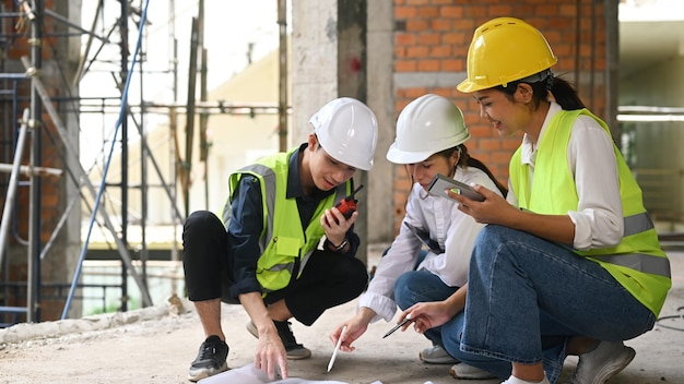 Bauingenieurteam und Vorgesetzter sitzen auf der Baustelle und diskutieren beim Besuch eines neuen Gebäudes über den Plan