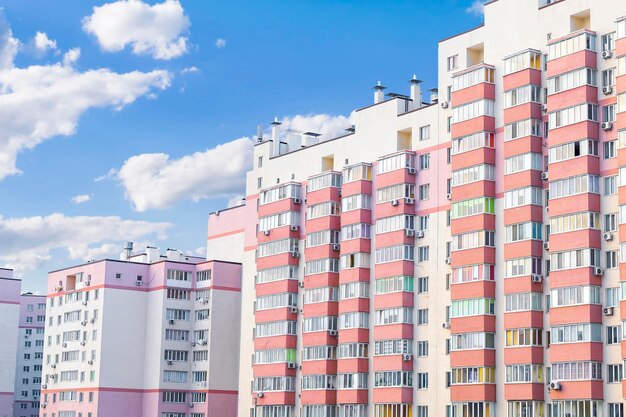 Baukomplex hohe rosafarbene Wohngebäude mit vielen Fenstern und Balkonen im Wohngebiet der Stadt gegen den blauen Himmel. Immobilien-Entwicklung