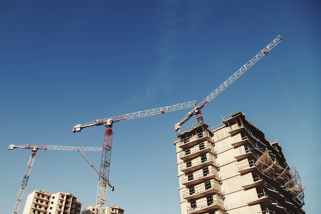 Baukräne arbeiten auf der Baustelle vor Himmelshintergrund