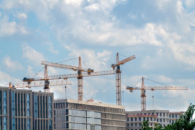 Baukräne in der Nähe der Fassade eines im Bau befindlichen Hauses moderne Bauindustrie Verkauf und Vermietung von Immobilien