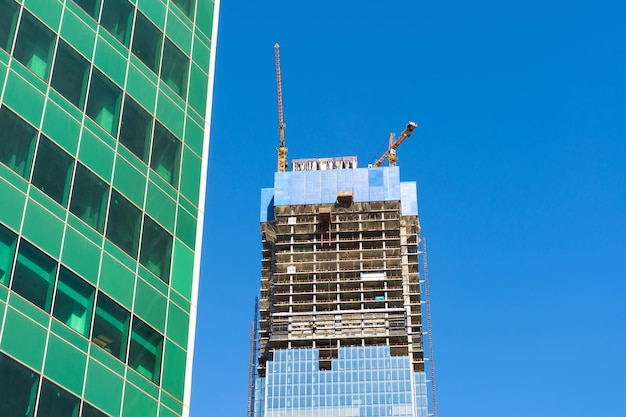 Baukran auf dem Bau eines Wolkenkratzer-Wohnhauses, auf einem Hintergrund aus Glasstruktur von Fenstern von Finanzbüros.