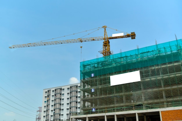 Baukran auf einer Baustelle gegen Hintergrund des blauen Himmels