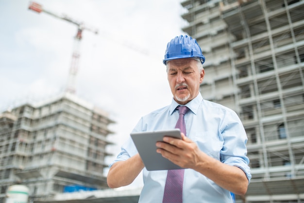 Bauleiter mit seinem Tablet vor einer Baustelle