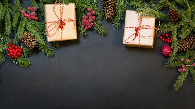 Baum, Geschenke, Stechpalmenbeeren und Dekoration auf einer schwarzen Tafel.