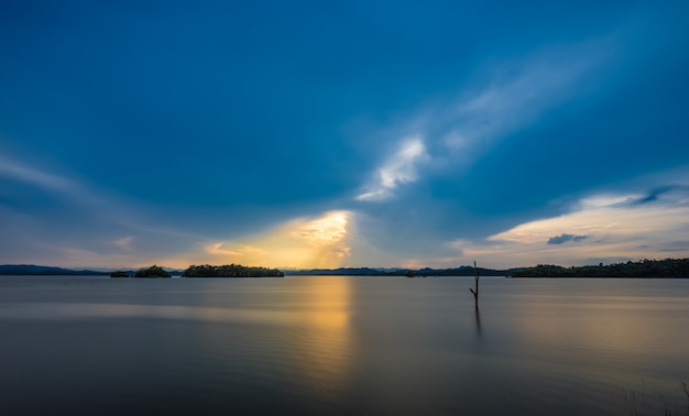 Baum im See- und Sonnenunterganghintergrund