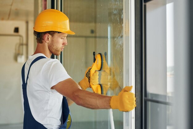 Baumeister bei seiner Arbeit Junger Mann, der tagsüber in Uniform am Bau arbeitet