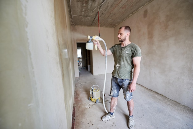 Baumeister malt mit Airbrush-Wandhausreparatur Im Hintergrund ist ein großes Arbeitsvolumen zu sehen