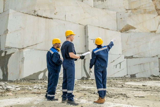 Baumeisterin, die während des Gesprächs mit Männern auf unvollendete Wand des Gebäudes zeigt