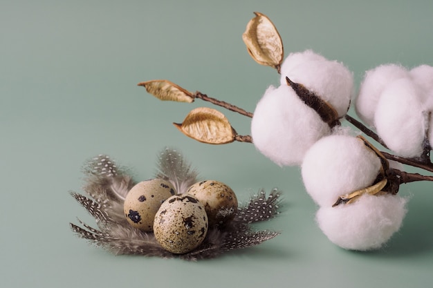 Baumwolle, Ostern Wachteleier in einem Nest aus Federn auf blauem Grund. Ostern schöne Komposition, Postkarte. Ostern-Konzept, Hintergrund.