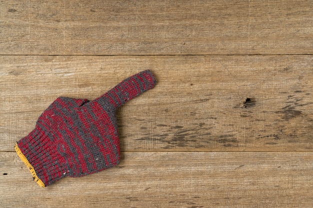 Baumwollhandschuh zeigen Zeigefingerzeichen auf schäbigem Holzbrett.