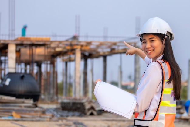 Bauplanarchitekt des Bauingenieurs der asiatischen Frau, der weißen Sicherheitshelm trägt