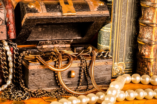 Foto baús de tesouro com ouro. pérolas e correntes de ouro. estilo vintage.