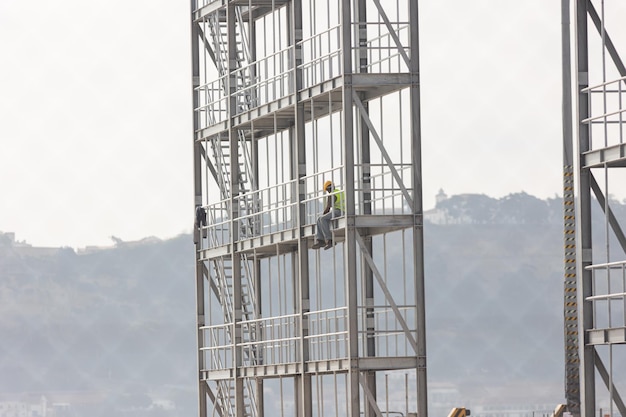 Baustelle Ein schwarzer Arbeiter sitzt auf Höhe des Gebäuderahmens