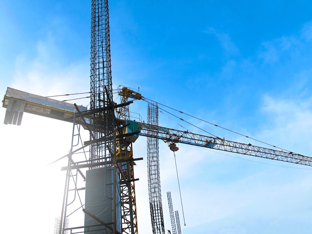 Baustelle mit dem Kran, der an einem Gebäude im Hintergrund des blauen Himmels arbeitet