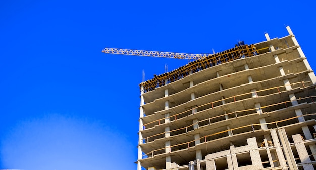 Baustelle mit Hochbaukränen auf einem Hintergrundfoto des blauen Himmels