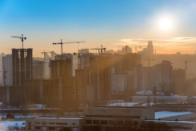 Baustelle mit Industriekränen in der Stadt bei Sonnenuntergang