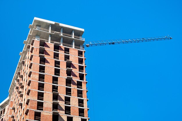 Baustelle mit Kran gegen den blauen Himmel Bau eines mehrstöckigen Gebäudes