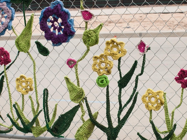 Bauzaun bedeckt mit gehäkelten Gartenkreaturen wie Käfern und Blumen von der Ladies Fancywork Society. Baustelle der Union Station in Denver, Colorado.