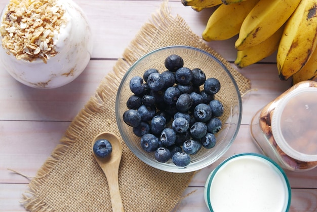 Baya azul fresca en un tazón con leche de plátano y almendras en la mesa