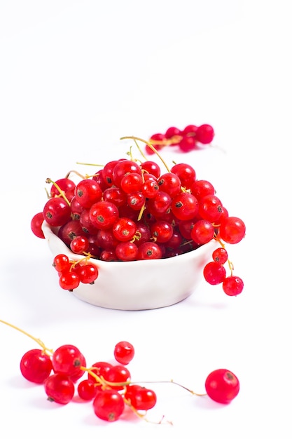 Baya de la grosella roja de la fruta del verano en taza de cerámica en el fondo blanco con el espacio de la copia