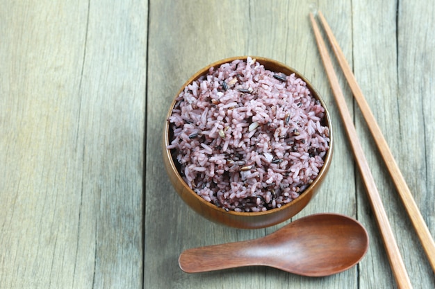 Baya orgánica del arroz en plato de madera en el fondo de madera.