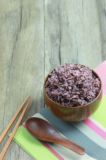 Baya orgánica del arroz en plato de madera en el fondo de madera.