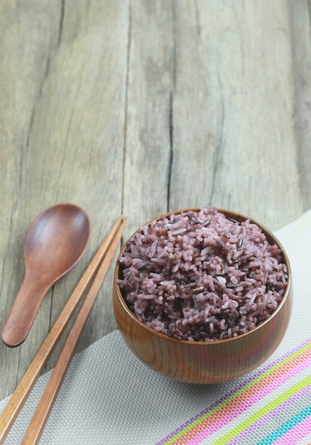 Baya orgánica del arroz en plato de madera en el fondo de madera.