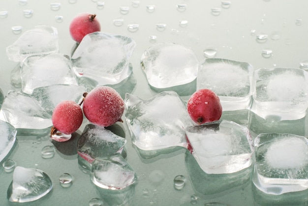 Baya roja congelada con cubitos de hielo sobre superficie verde brillante