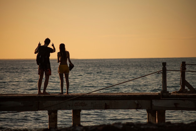 BAYAHIBE, REPÚBLICA DOMINICANA, 13 de dezembro de 2019: jovem casal apaixonado no cais em Susnset