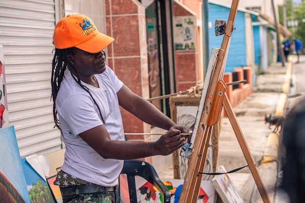 BAYAHIBE, REPÚBLICA DOMINICANA 21 DE ENERO DE 2020: Artista callejero pintor dominicano en Bayahibe