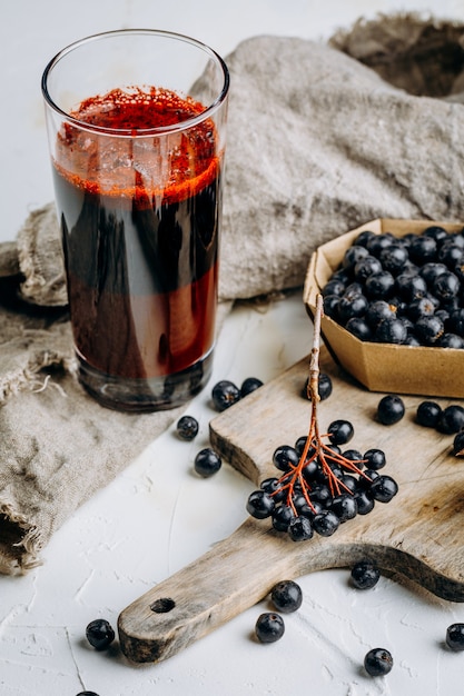 Bayas de aronia frescas y jugo de bayas en un vaso.