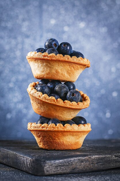 Bayas azules del endrino en tartlets de la arena en una tabla.