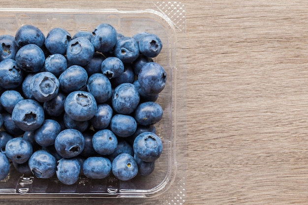 Bayas azules frescas en envases de plástico Bayas jugosas dulces saludables en la mesa de madera