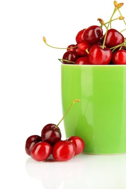 Bayas de cereza roja madura en taza aislado en blanco