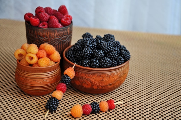 bayas de colores de frambuesas rojas amarillas y negras o moras en loza