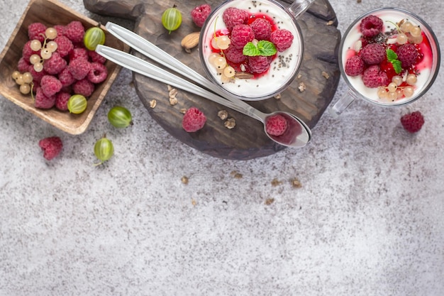 Bayas de frambuesa frescas con yogur o crema en vasos Concepto de postre de desayuno de verano