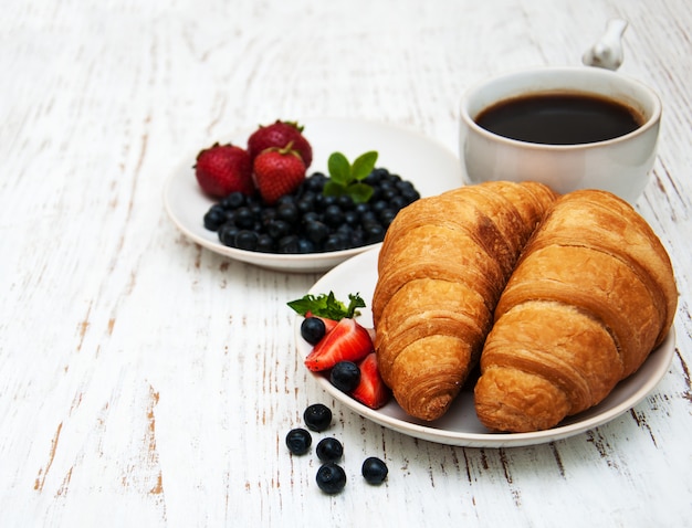 Bayas frescas, café y croissant.