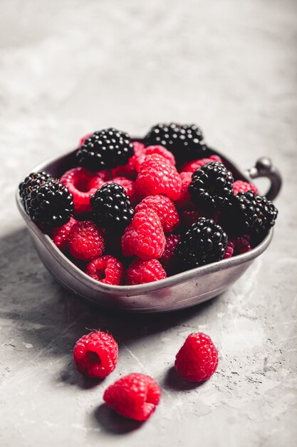 Bayas frescas frambuesas, moras sobre un fondo de arte gris. Comida sana, bayas de verano, comida adelgazante.