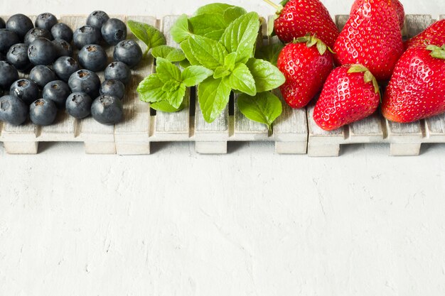 Bayas frescas fresas menta menta en un soporte de madera