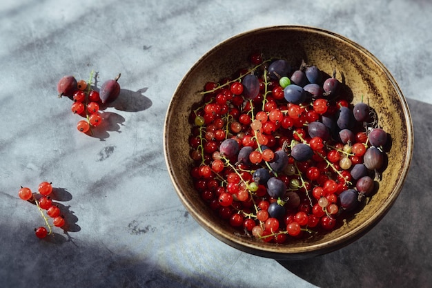 Foto bayas frescas de verano en un plato sobre un fondo de hormigón grosellas rojas y grosellas