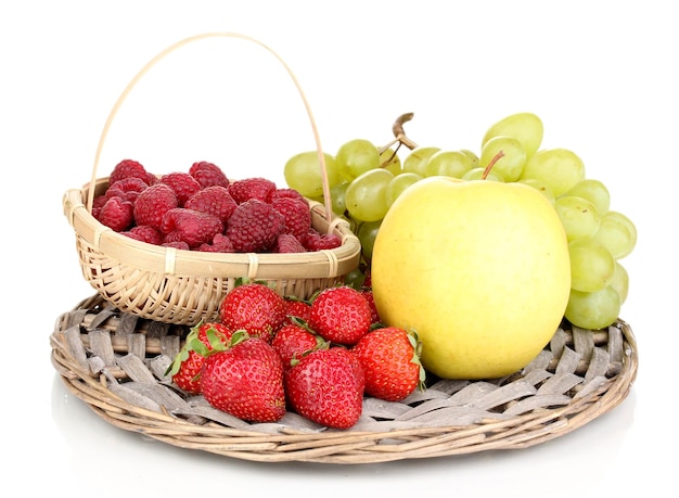 Bayas y frutas dulces maduras en estera de mimbre aislado en blanco