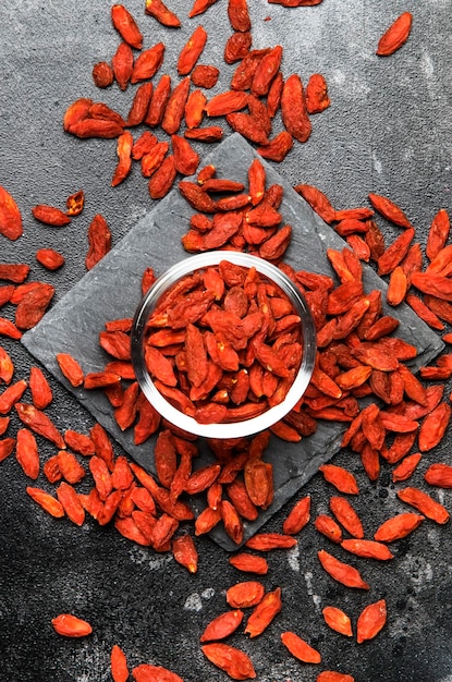 Bayas de goji rojas secas sobre fondo gris concepto de comida útil y saludable diseño plano con el lugar para la vista superior del texto