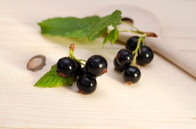 Bayas de grosella negra con hojas de cerca sobre un fondo de madera