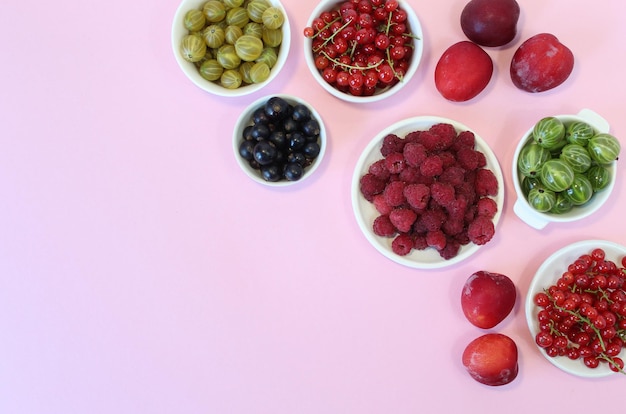 Foto bayas mixtas en plato de concreto sobre fondo rosa con plato vacío y espacio para copiar