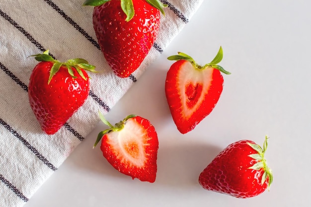 Bayas rojas de fresas frescas en una toalla de cocina sobre la mesa fresas cortadas