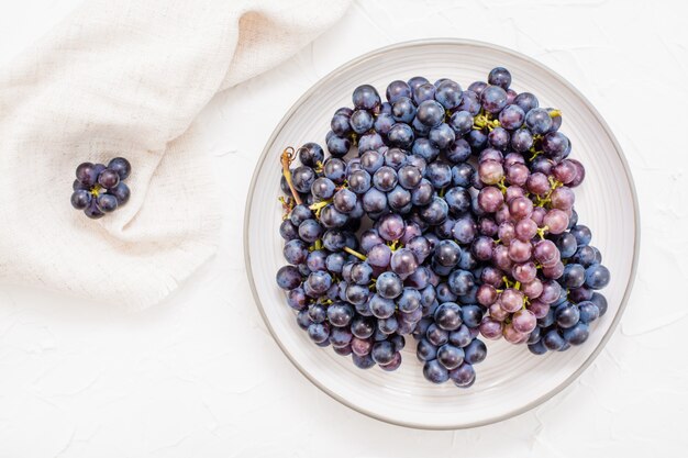 Bayas de uvas azules maduras en un plato sobre una mesa.