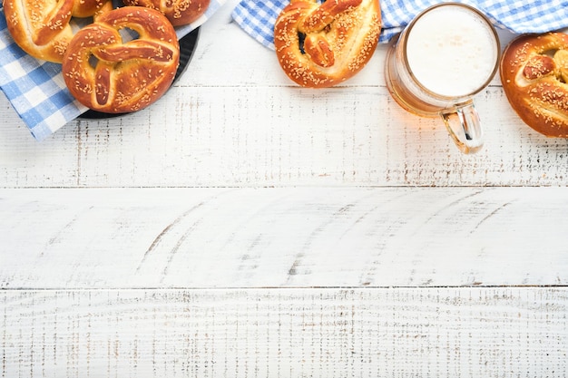 Bayerische Brezeln und ein Glas Lagerbier Oktoberfest-Speisekarte traditionelle gesalzene Brezeln über altem weißem Holzhintergrund Draufsicht mit Platz für Text Oktoberfest-Thema