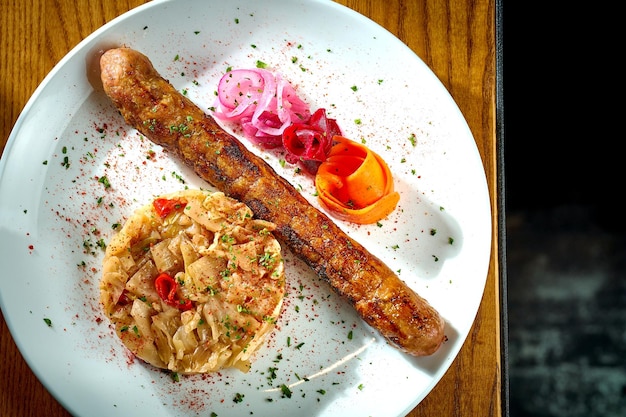 Bayerische Fleischwurst mit einer Beilage aus gedünsteten Sauerkrautzwiebeln in einem Teller auf Holzhintergrund