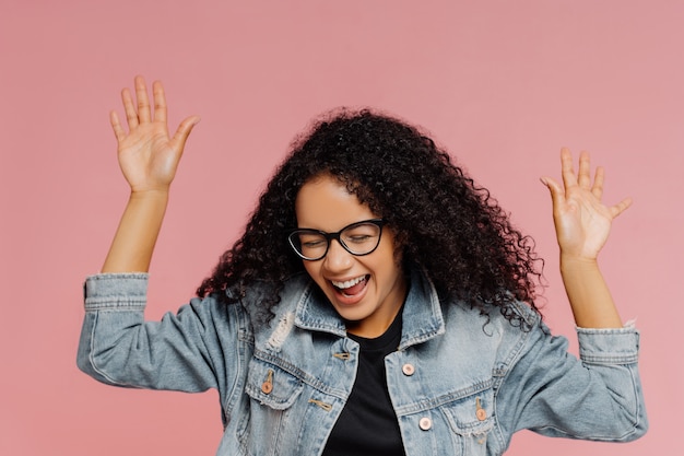 Bbeautiful glückliche Frau mit lockiger Frisur, hält die Hände hoch, lacht aus positiven Emotionen