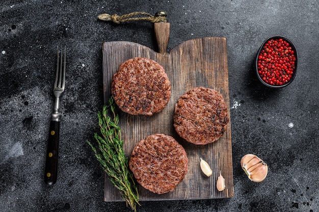 BBQ gegrillte Rindfleischfleisch Pastetchen für Burger aus Hackfleisch und Kräutern auf einem Holzbrett